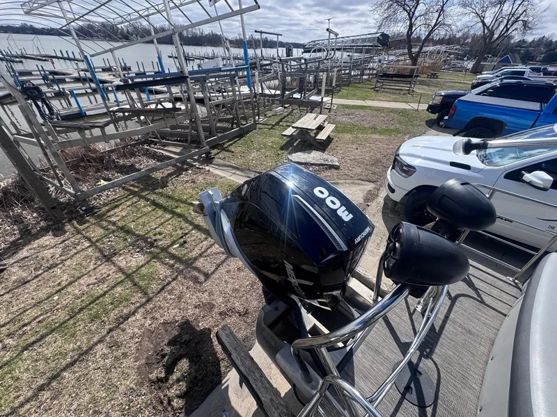 Slide: The Image of 2021 Sweetwater 2486SFL boat with a powerful outboard motor, parked near a lakeside dock. - 13