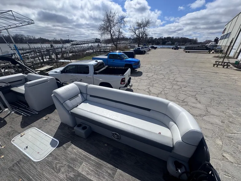 Slide: The Image of 2021 Sweetwater 2486SFL pontoon boat with gray seating, parked near a waterfront. - 5