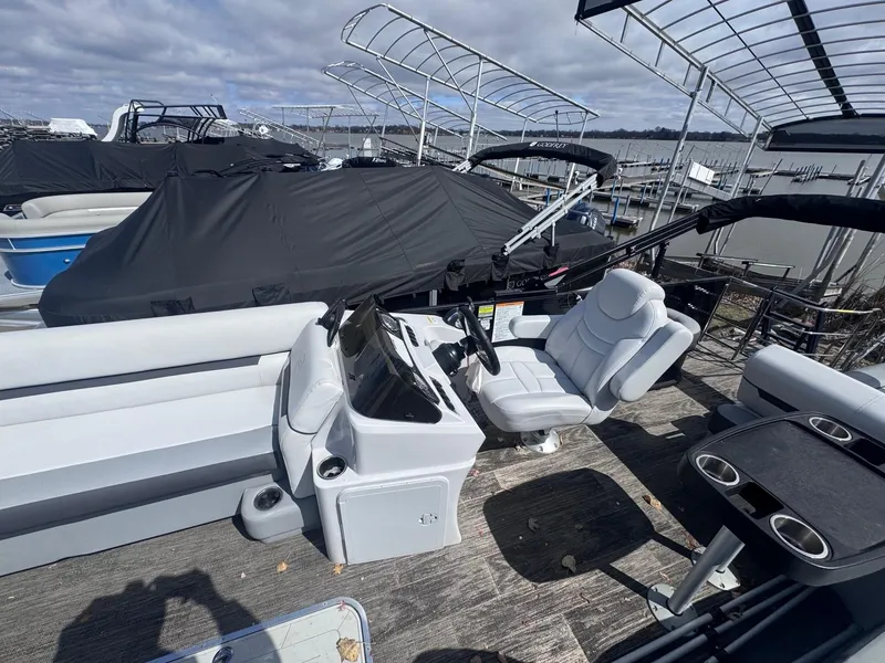 Slide: The Image of 2021 Sweetwater 2486SFL pontoon boat interior with helm, seating, and covered docked boats. - 7