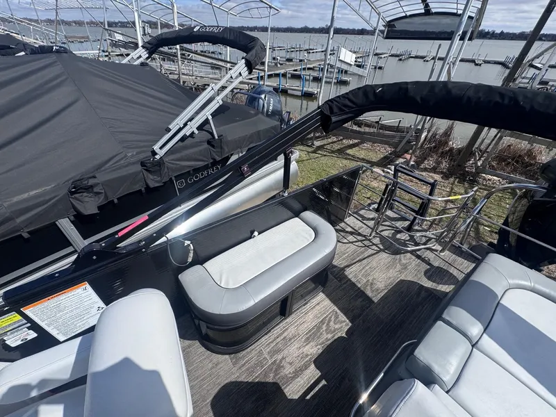 Slide: The Image of 2021 Sweetwater 2486SFL pontoon boat with gray seating and docked at a marina. - 9