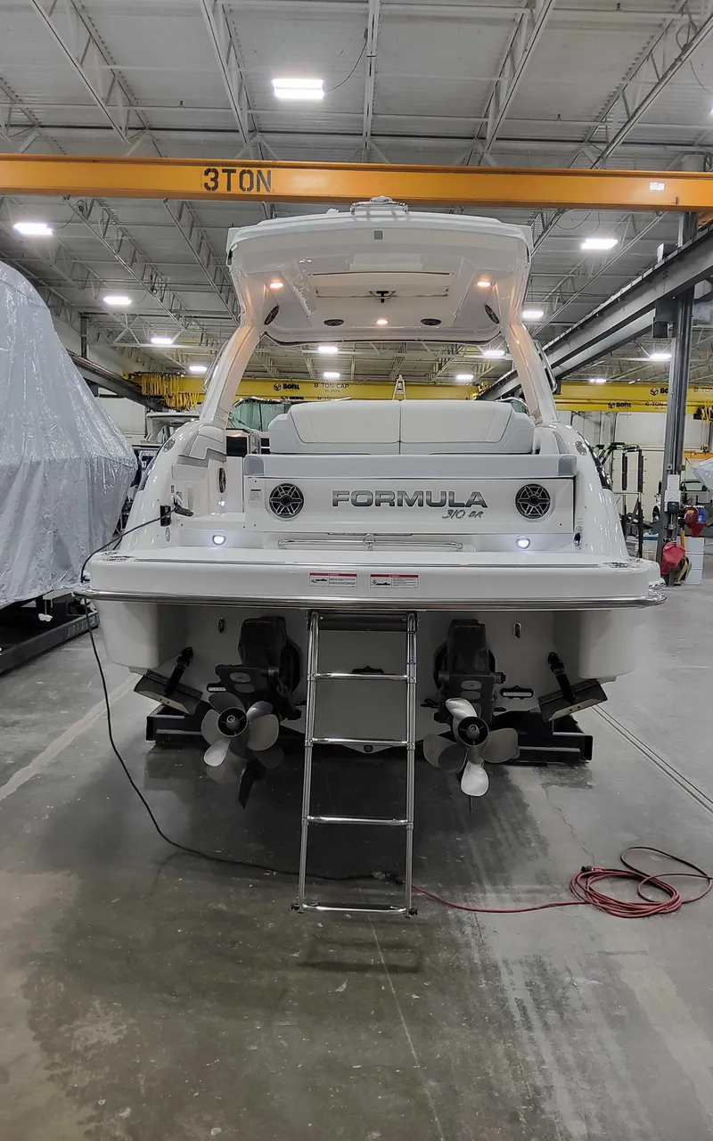 Slide: The Image of 2025 Formula 310 Bowrider boat in a warehouse, rear view with dual propellers. - 3