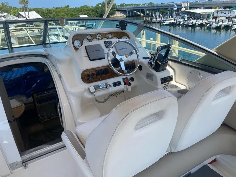 Slide: The Image of 2003 Larson 310 boat cockpit with steering wheel, gauges, and white seating at marina. - 15