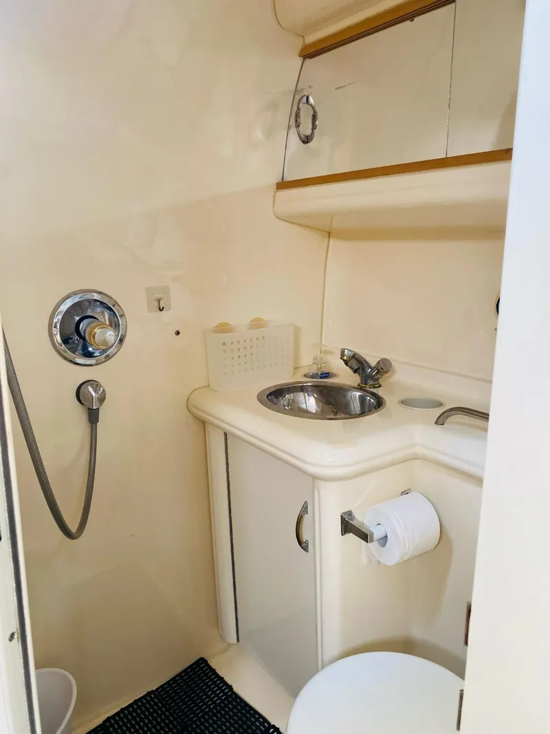 Slide: The Image of Compact bathroom in a 2003 Larson 310 boat, featuring sink, shower, and storage. - 19