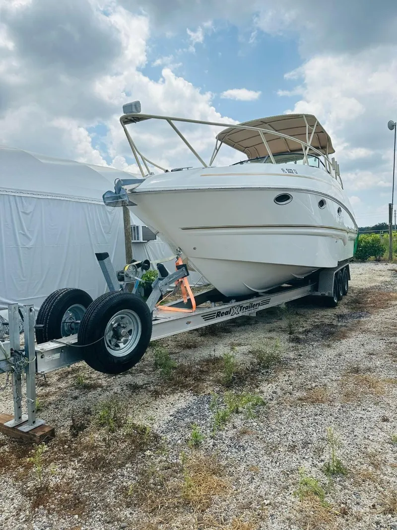 Slide: The Image of 2003 Larson 310 boat on trailer under cloudy sky. - 2