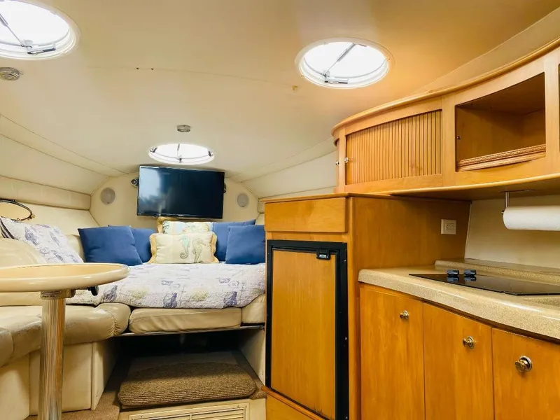 Slide: The Image of Cozy interior of 2003 Larson 310 boat with bed, TV, and kitchenette. - 5