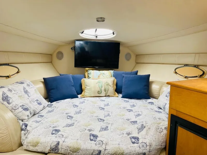Slide: The Image of Cozy cabin interior of 2003 Larson 310 boat with bed, pillows, and TV. - 9