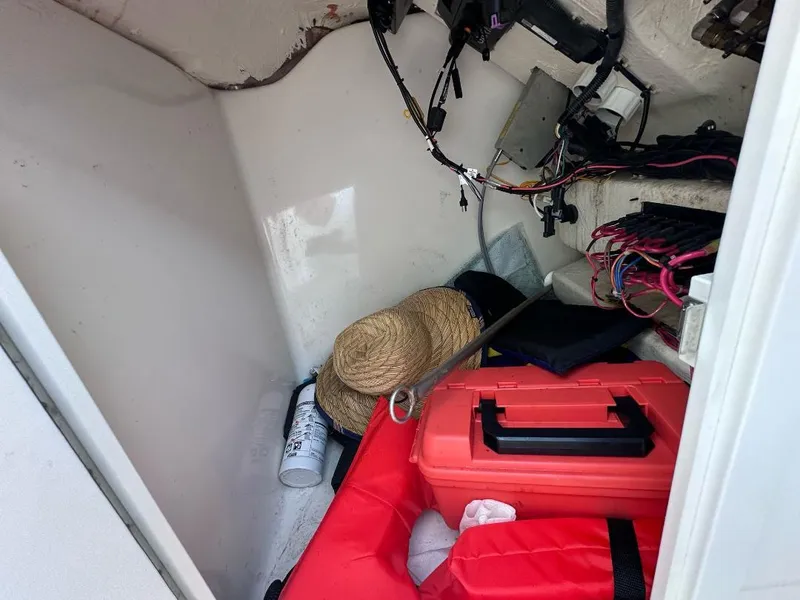 Slide: The Image of Storage compartment of 2022 Cobia 220 DC boat with tools and safety equipment. - 10