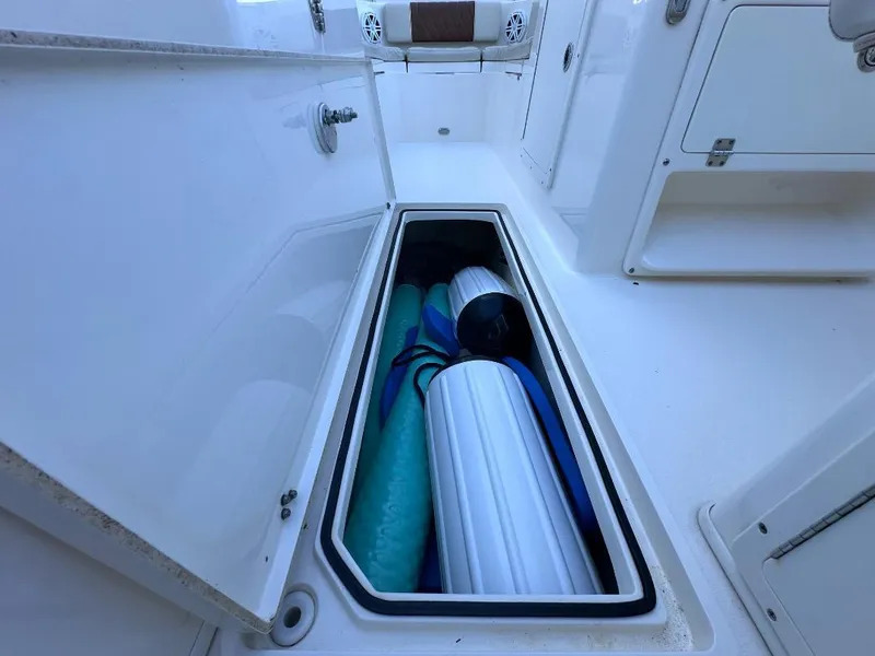 Slide: The Image of Storage compartment on a 2022 Cobia 220 DC boat, containing rolled-up mats. - 12