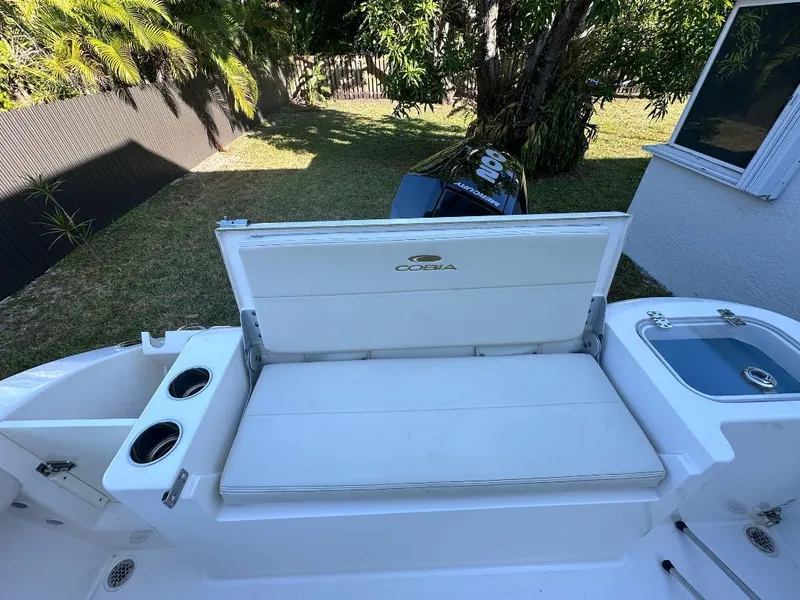 Slide: The Image of 2022 Cobia 220 DC boat with seating and cup holders in a backyard setting. - 13