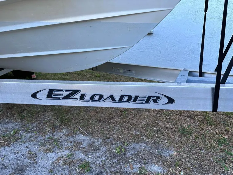 Slide: The Image of 2022 Cobia 220 DC boat on EZ Loader trailer, parked on grass. - 18