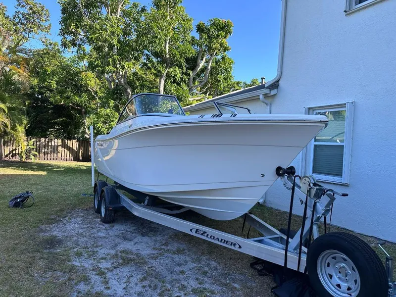 Slide: The Image of 2022 Cobia 220 DC boat on trailer beside house, surrounded by trees. - 4