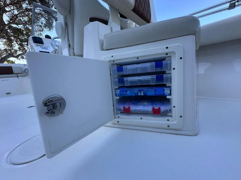 Slide: The Image of Open storage compartment on 2022 Cobia 220 DC boat with organized tackle boxes. - 8