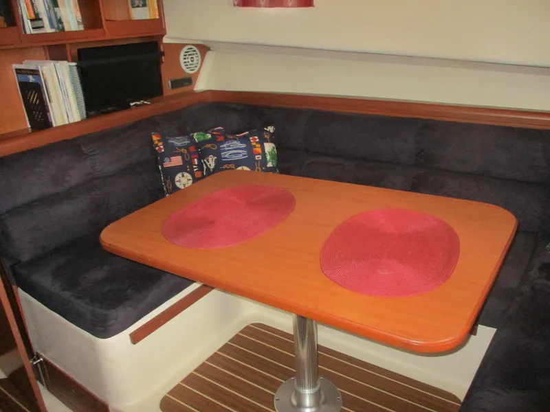 Slide: The Image of 2007 Mainship Pilot 34 Sedan interior with dining table, cushioned seating, and decorative pillows. - 11