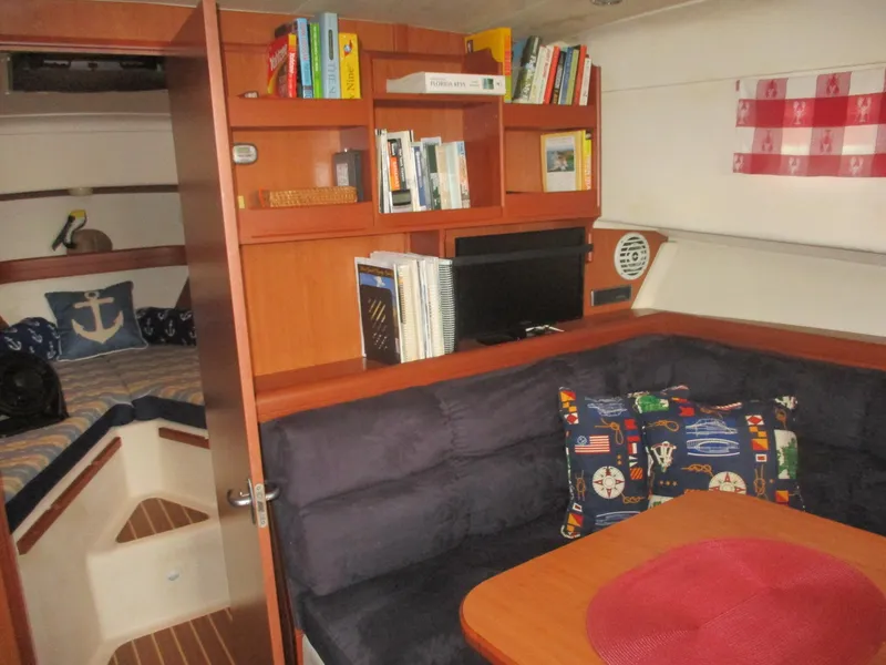 Slide: The Image of 2007 Mainship Pilot 34 Sedan interior with cozy seating, bookshelf, and nautical decor. - 12
