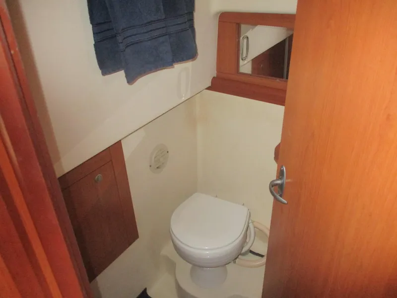 Slide: The Image of 2007 Mainship Pilot 34 Sedan bathroom with toilet, wooden cabinetry, and mirror. - 14