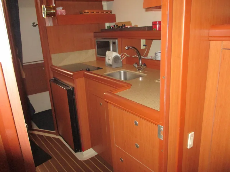 Slide: The Image of 2007 Mainship Pilot 34 Sedan interior kitchen with wood cabinetry and modern appliances. - 18