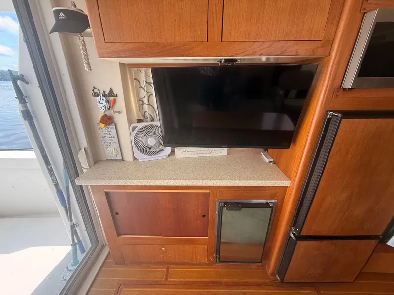 Slide: The Image of Interior of 2000 Mainship 390 Trawler with TV, fan, and wooden cabinetry. - 11
