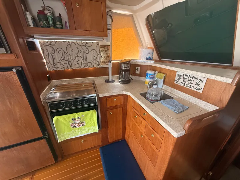 Slide: The Image of Cozy kitchen in 2000 Mainship 390 Trawler with stove, sink, and wooden cabinetry. - 13