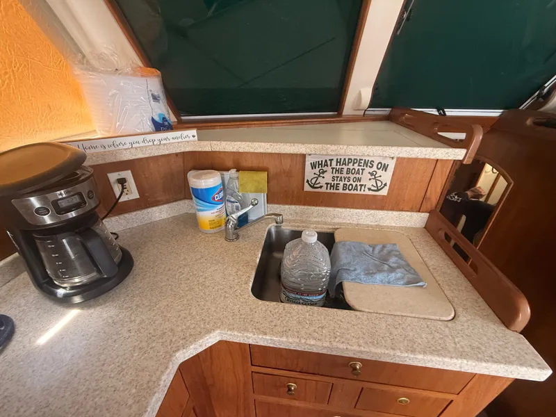 Slide: The Image of 2000 Mainship 390 Trawler kitchen with coffee maker, sink, and humorous sign. - 14