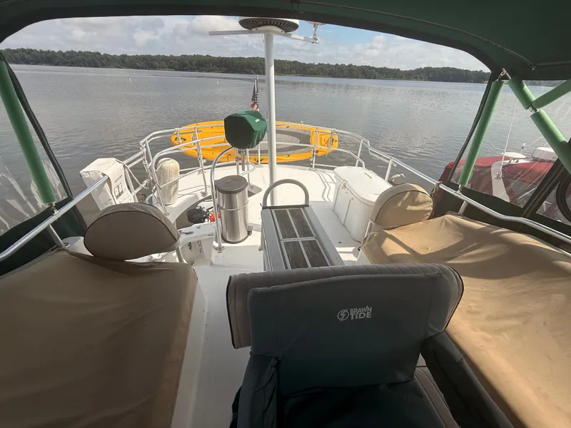 Slide: The Image of 2000 Mainship 390 Trawler deck with seating, overlooking calm waters and shoreline. - 20