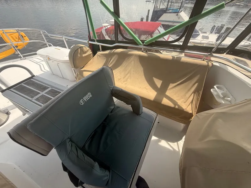 Slide: The Image of 2000 Mainship 390 Trawler deck with seating and protective covers, docked by the water. - 21