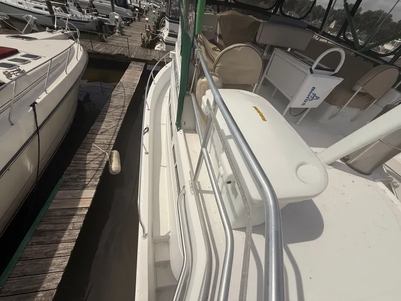 Slide: The Image of 2000 Mainship 390 Trawler docked at marina, featuring spacious deck and seating area. - 30