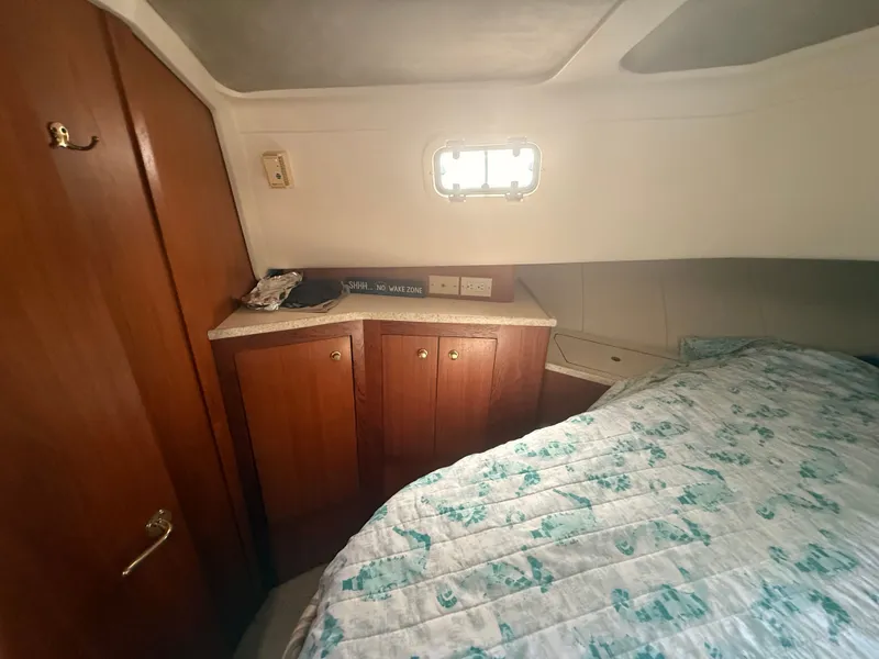 Slide: The Image of Cozy cabin interior of 2000 Mainship 390 Trawler with wooden cabinets and patterned bedding. - 38