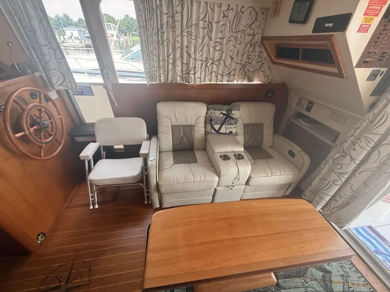 Slide: The Image of Interior of 2000 Mainship 390 Trawler with seating, wooden table, and nautical decor. - 8