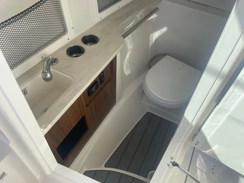 Slide: The Image of 2023 Sailfish 245 DC boat interior with sink, toilet, and storage. - 21