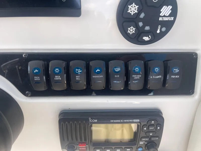 Slide: The Image of Control panel of a 2023 Sailfish 245 DC boat with labeled switches and radio. - 28