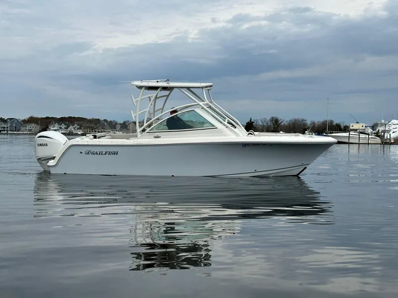 Slide: The Image of 2023 Sailfish 245 DC boat on calm water under cloudy sky. - 3