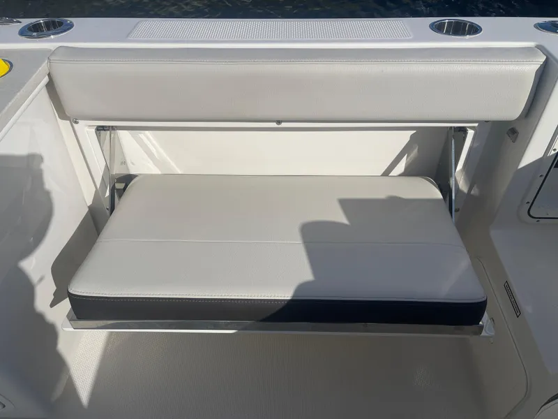 Slide: The Image of 2023 Sailfish 245 DC boat seat with storage compartment, featuring sleek design and cup holders. - 37