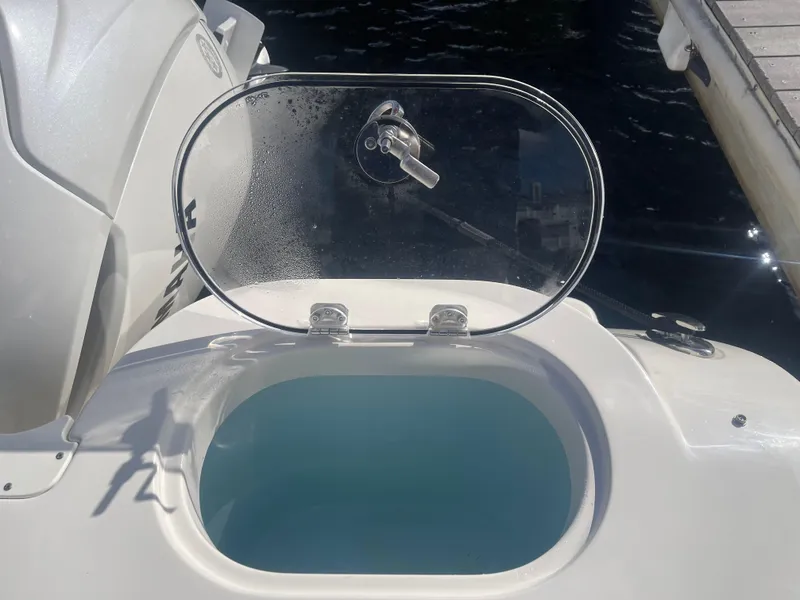 Slide: The Image of 2023 Sailfish 245 DC boat livewell with open lid, dockside view. - 48
