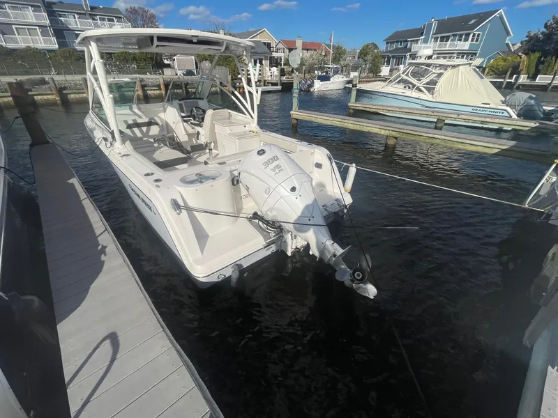 Slide: The Image of 2023 Sailfish 245 DC boat docked at marina, clear sky, waterfront homes in background. - 50