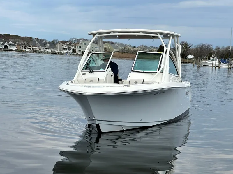 Slide: The Image of 2023 Sailfish 245 DC boat on calm water near residential shoreline. - 9
