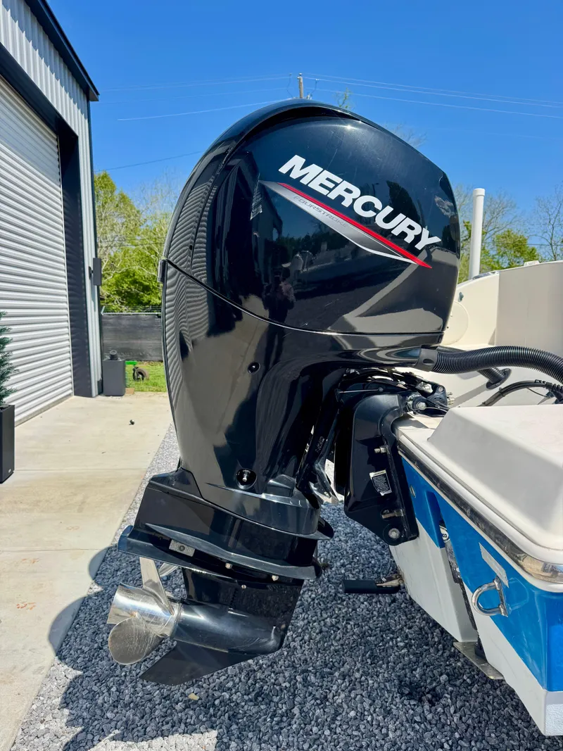 Slide: The Image of 2019 Cobia 261 boat with Mercury outboard motor, parked outdoors on gravel. - 4