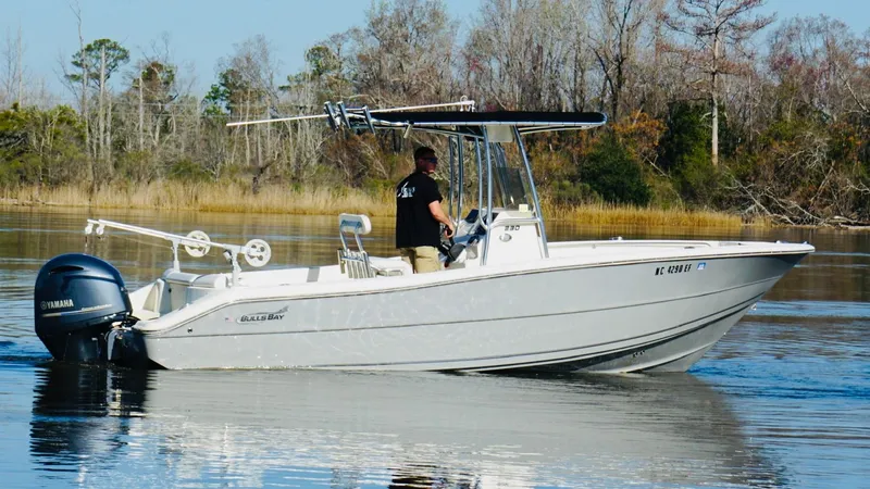 Slide: The Image of 2017 Bulls Bay 230 Center Console boat on calm water with trees in the background. - 18