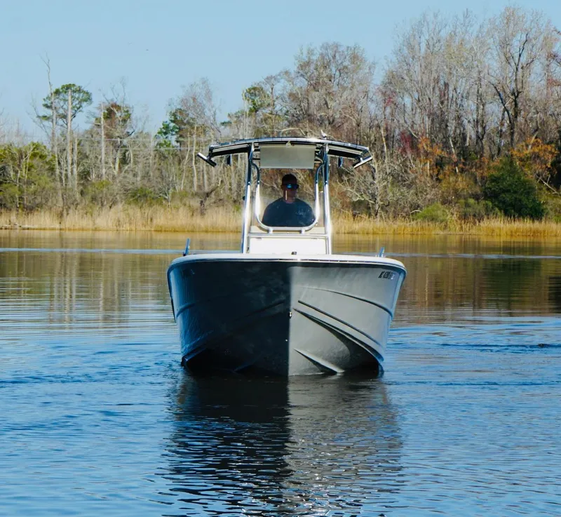 Slide: The Image of 2017 Bulls Bay 230 Center Console boat on calm water, surrounded by trees. - 4