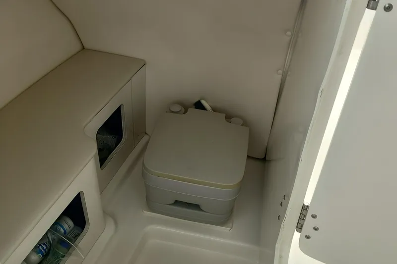 Slide: The Image of 2016 Robalo R247 Dual Console interior with portable toilet and storage compartments. - 13