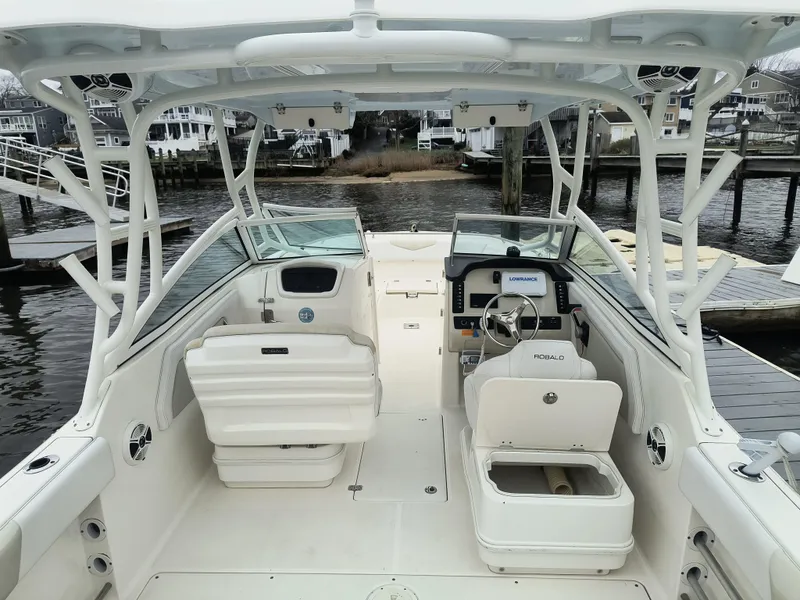 Slide: The Image of 2016 Robalo R247 Dual Console boat interior at dock, featuring helm and seating. - 7