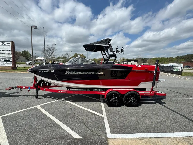 Slide: The Image of 2021 Moomba Mojo boat on red trailer in parking lot under cloudy sky. - 2