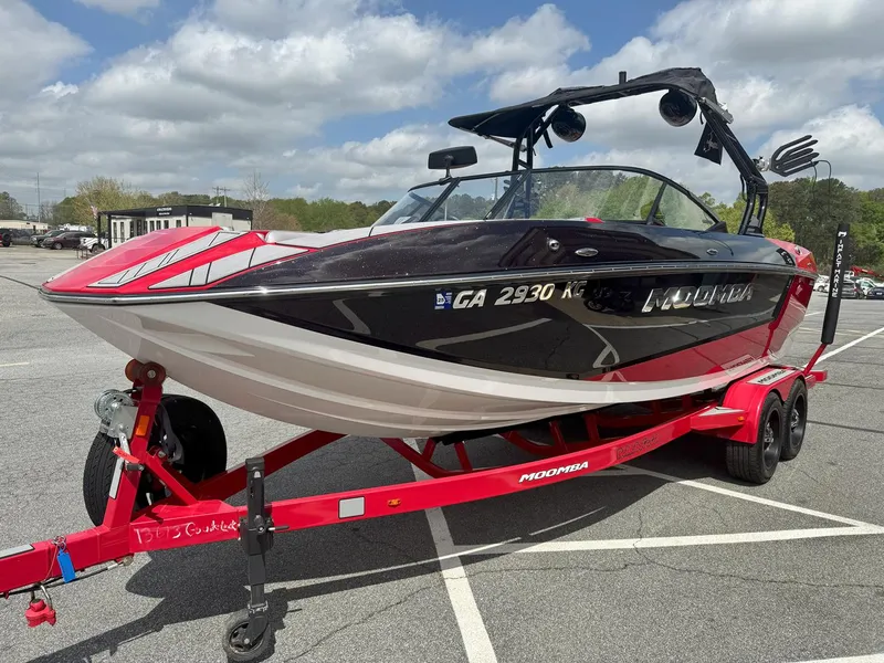 Slide: The Image of 2021 Moomba Mojo boat on red trailer in parking lot, under cloudy sky. - 3
