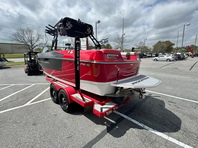 Slide: The Image of 2021 Moomba Mojo boat on trailer in parking lot, red and white design, overcast sky. - 5