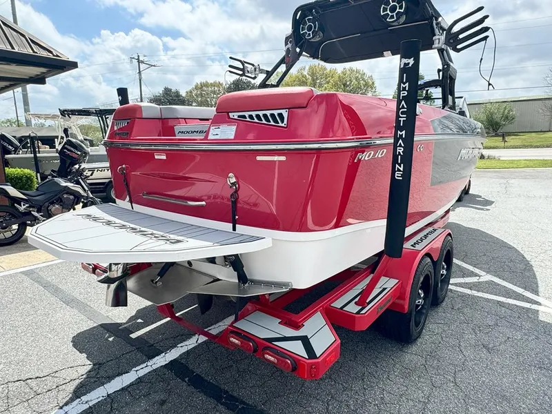 Slide: The Image of 2021 Moomba Mojo boat in vibrant red, parked on a trailer in a lot. - 7