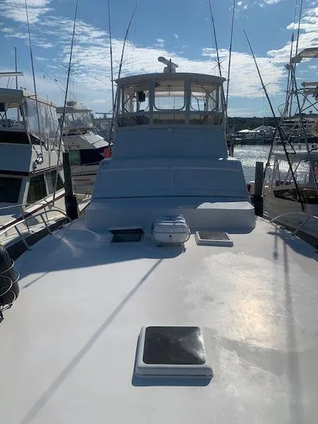 Slide: The Image of 1984 Post Convertible boat docked, showcasing spacious deck and cabin under clear sky. - 10