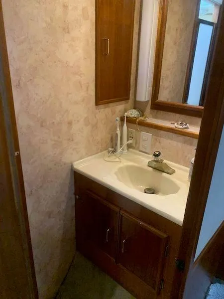 Slide: The Image of Compact bathroom with wooden cabinets and a beige countertop sink. - 20