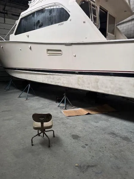 Slide: The Image of 1984 Post Convertible boat on stands in a garage, with a small chair nearby. - 33
