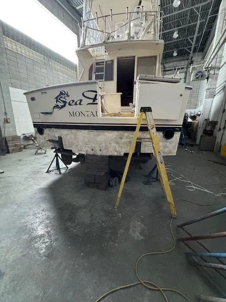 Slide: The Image of 1984 Post Convertible boat in a workshop, labeled "Sea D" Montauk, with ladder and maintenance equipment. - 35