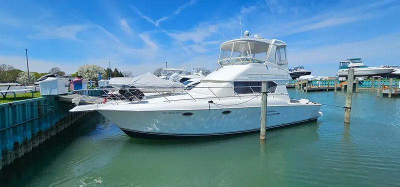 Slide: The Image of 2003 Silverton 42 Convertible yacht docked in a marina under a clear blue sky. - 0
