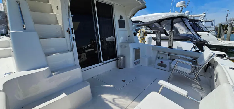 Slide: The Image of 2003 Silverton 42 Convertible yacht deck with seating and stairs, docked at marina. - 12